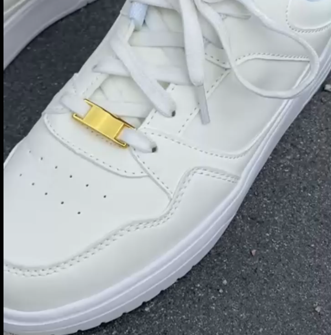 Weiße Sneaker mit goldenem Sneakeez Schuhcharm auf Asphalt – minimalistischer Schuhschmuck in edlem Look für elegante Sneaker-Styles